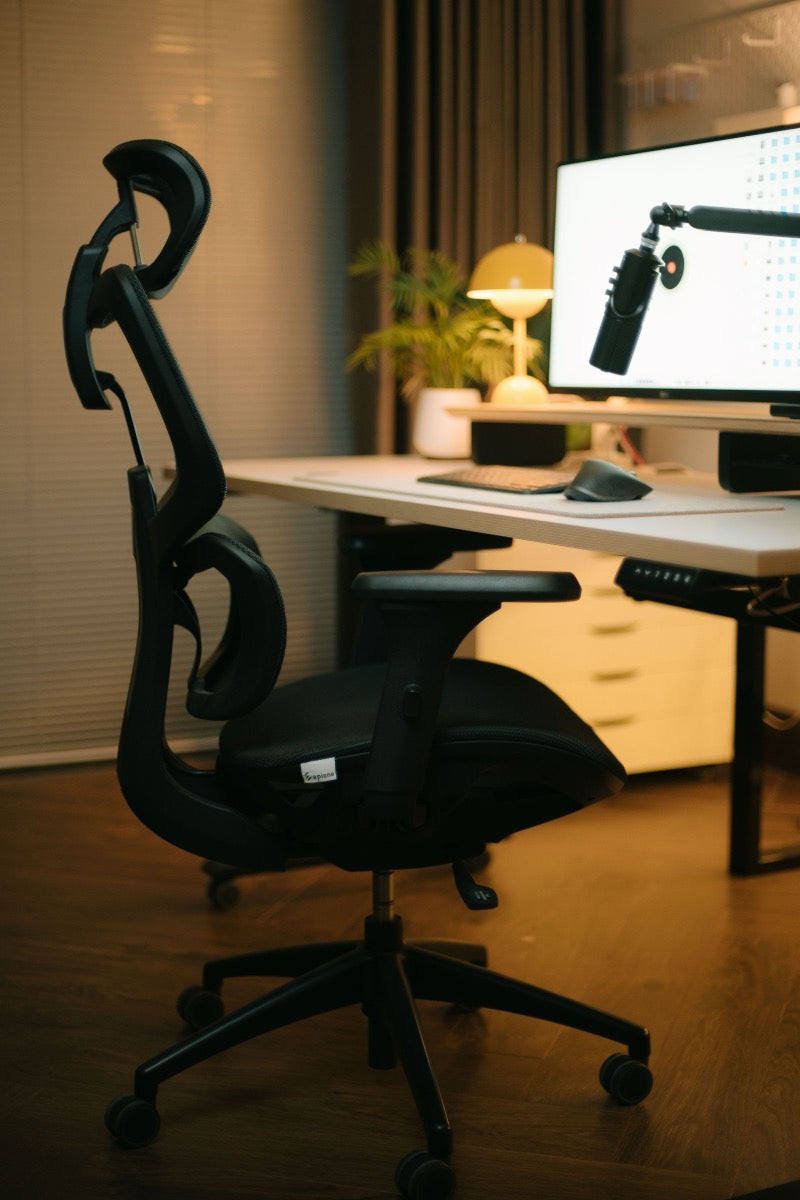Ergonomiška biuro kėdė su galvos atrama prie reguliuojamo aukščio stalo